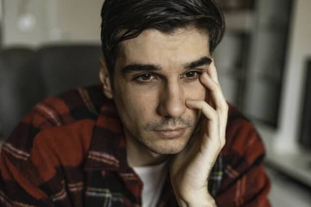 Sad unhappy handsome man sitting on the sofa