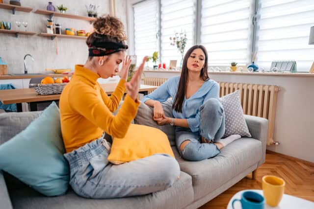 two female friends arguing on the couch