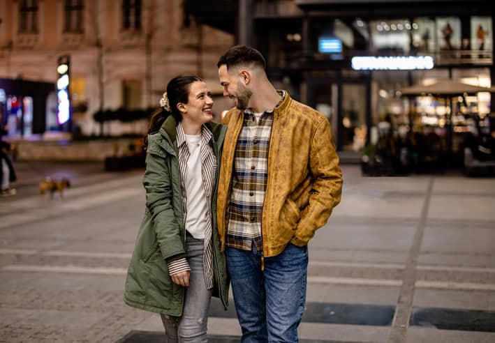 A couple takes a quiet walk at night, hugging each other and enjoying each other's company in a loving embrace