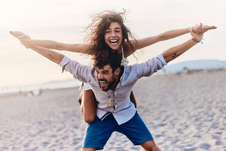 Young couple having fun while piggybacking \on the beach.
