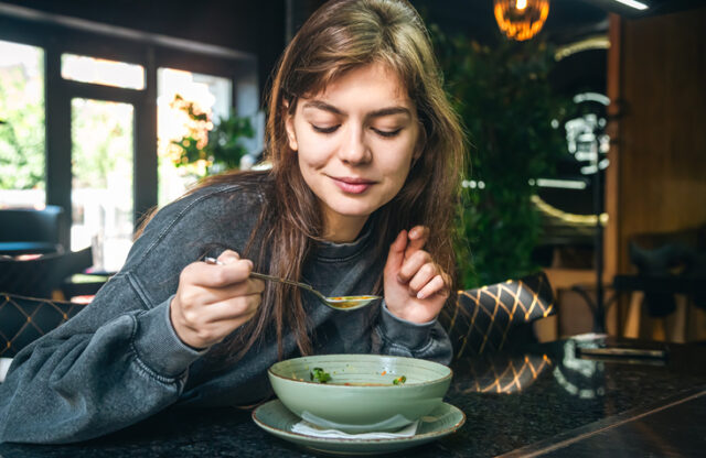 Woman eating soup at cafe.
