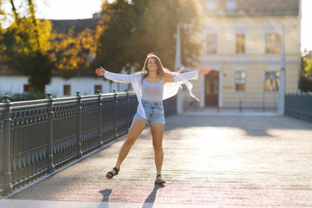 Woman having fun rotating herself on bridge above Ljubljanica River.