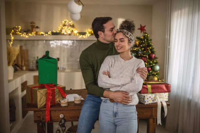 man kissing girlfriend's head christmas