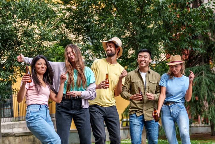 Group of friends laughing at a sunny outdoor gathering.