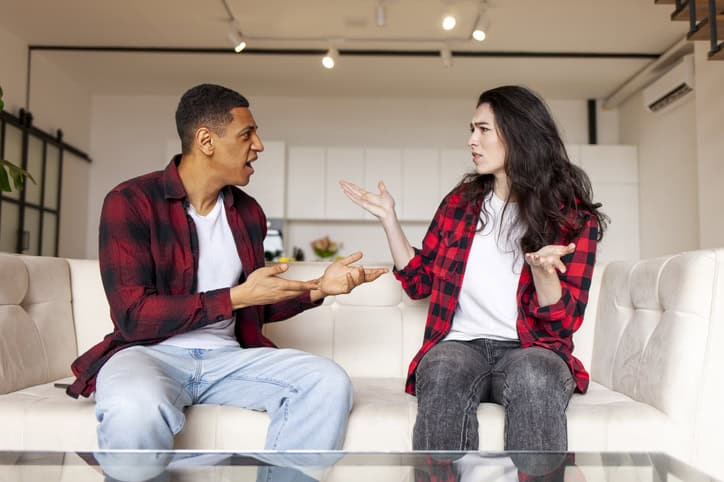 amily quarrel and scandal, young interracial married couple swear and conflict at home on the couch, relationship problems, husband yells at wife
