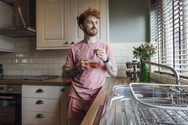 Man standing in his kitchen in the morning.