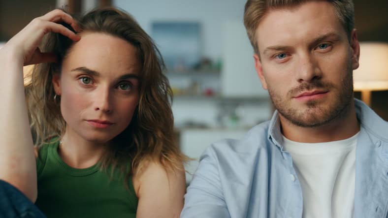Focused pair staring tv show at home closeup. Man hand holding remote controller