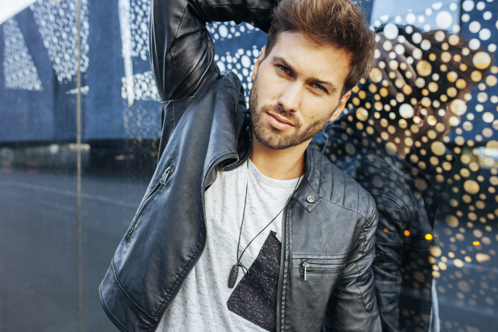 Young stylish man posing in casual wear over glass wall