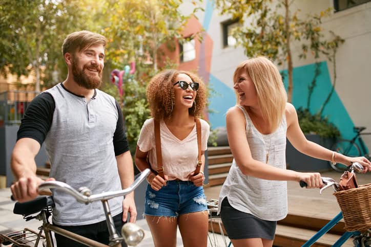 three friends walking with bikes outside