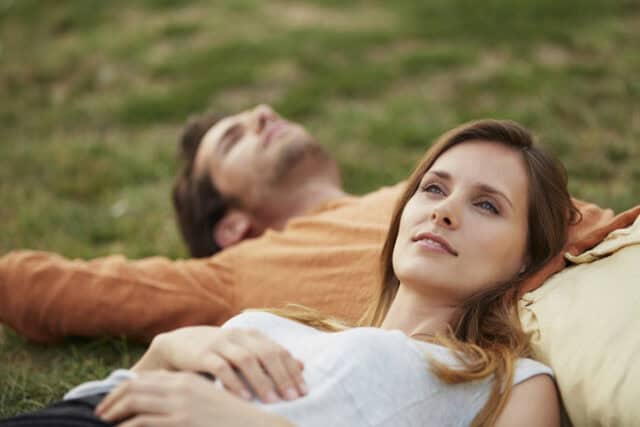 man, woman lying in grass daydreaming