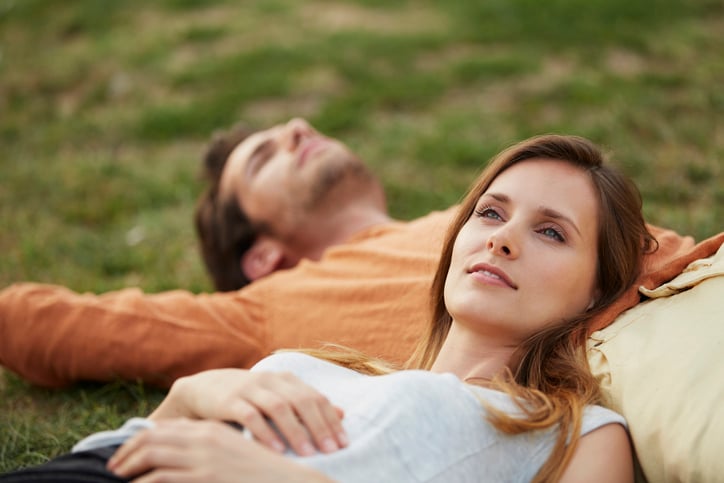 man and woman lying in grass daydreaming, Woman resting head on man's stomach at park