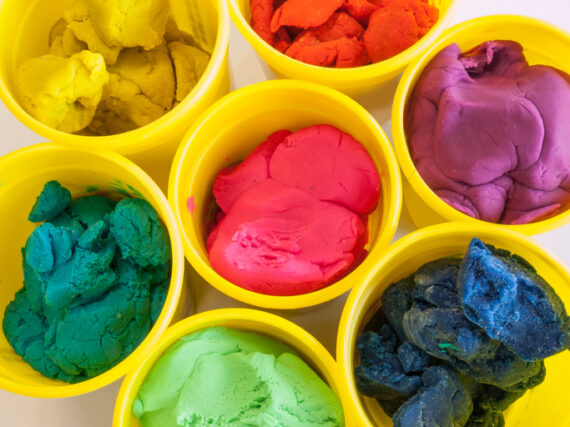 Colorful play dough in yellow cans in white background.
