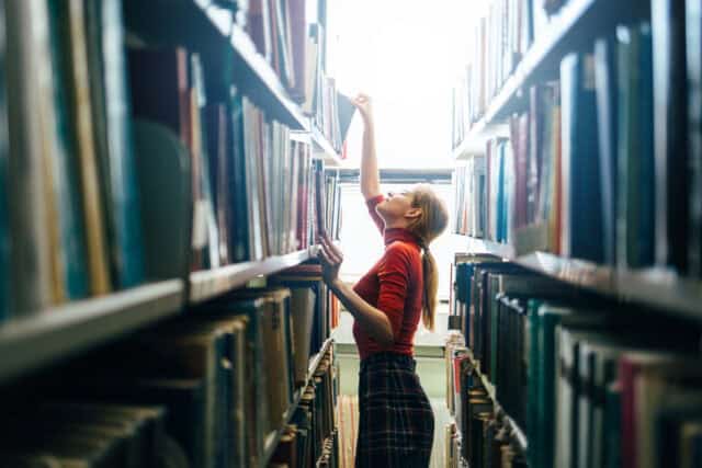 Woman choosing a book from bookshelf.