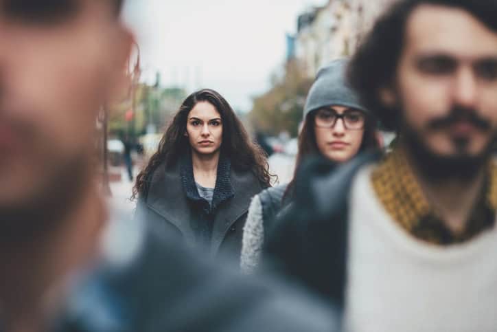 Serious woman among other defocused faces on the street.