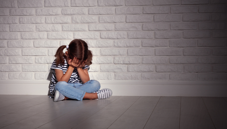 Sad little girl crying into her hands