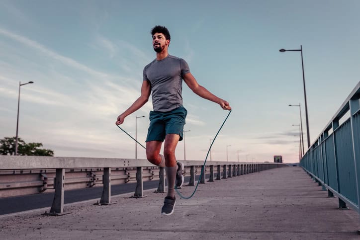 Young man jumping rope outside.