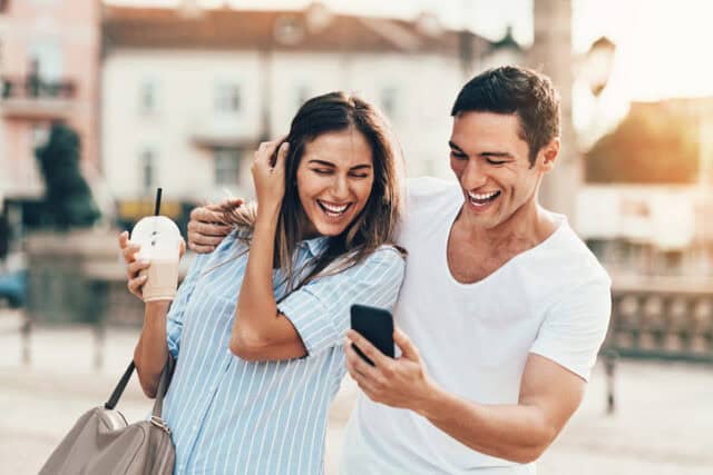 Young couple looking at a smart phone outdoors in the city