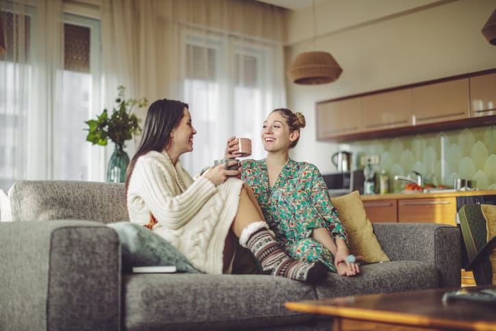 Two women sitting at home in PJs.