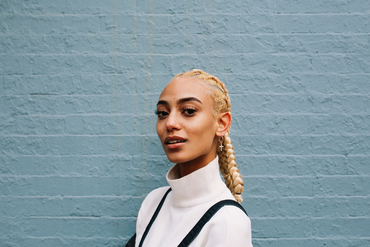 Young woman standing against a brick wall.