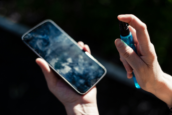 Person cleaning a mobile phone screen.