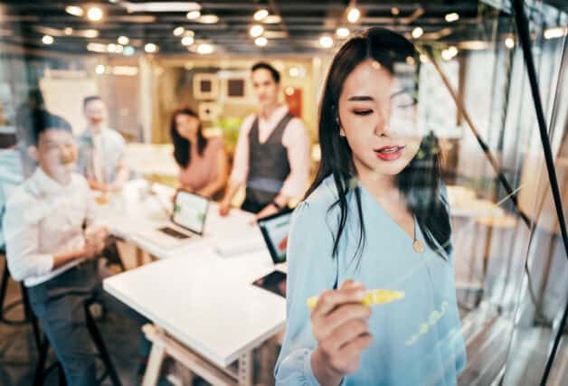 woman writing on board in business meeting