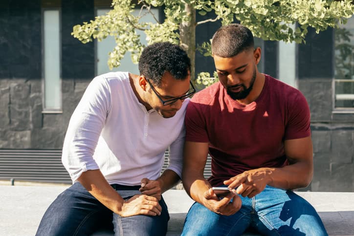 Two men looking together at phone.