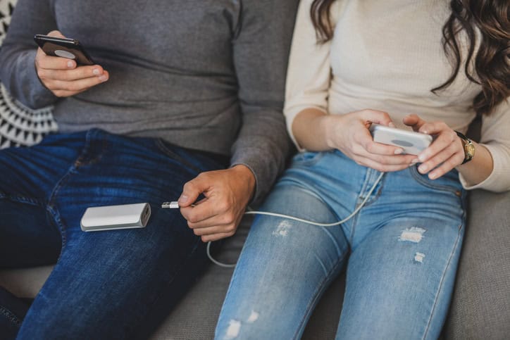 Couple charging smart phones with power bank