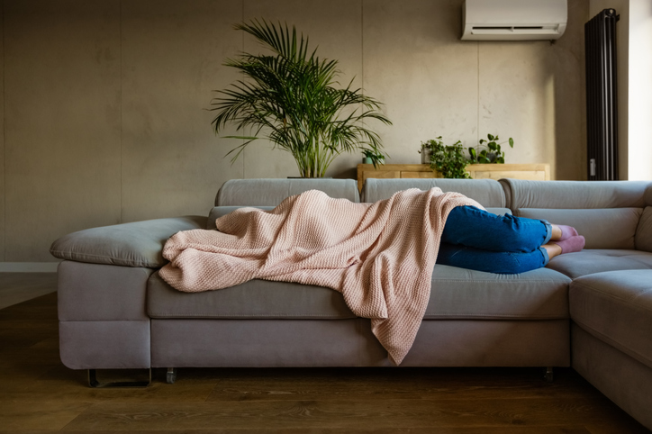 Woman sleeping on couch with blanket.