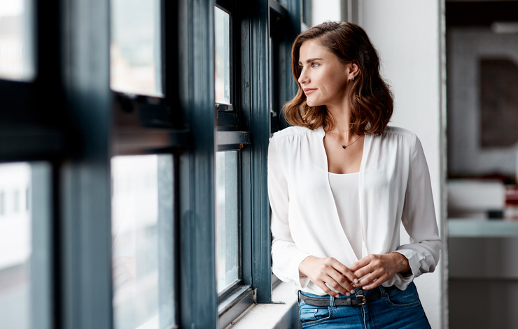 Confident young businesswoman looking out the window.