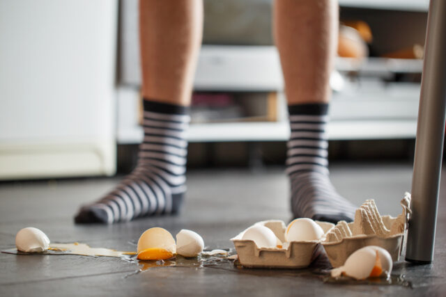 Broken eggs in front of the refrigerator.