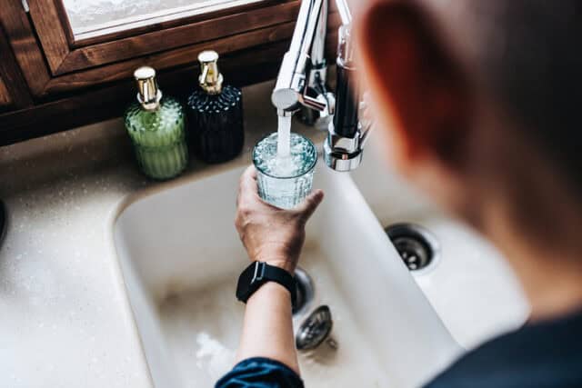 Man filling a glass of filtered water from the tap.