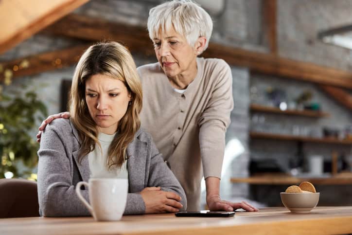 Adult woman with her mom standing over her.