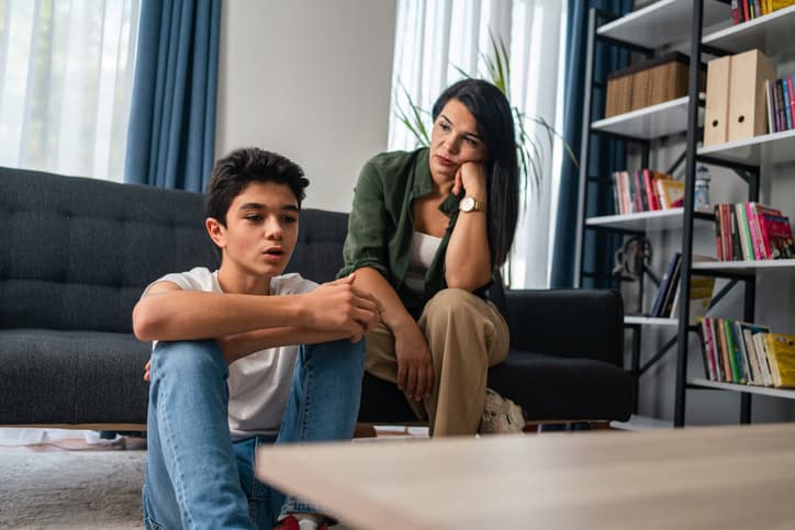 Teen boy talking to his mom in the living room.