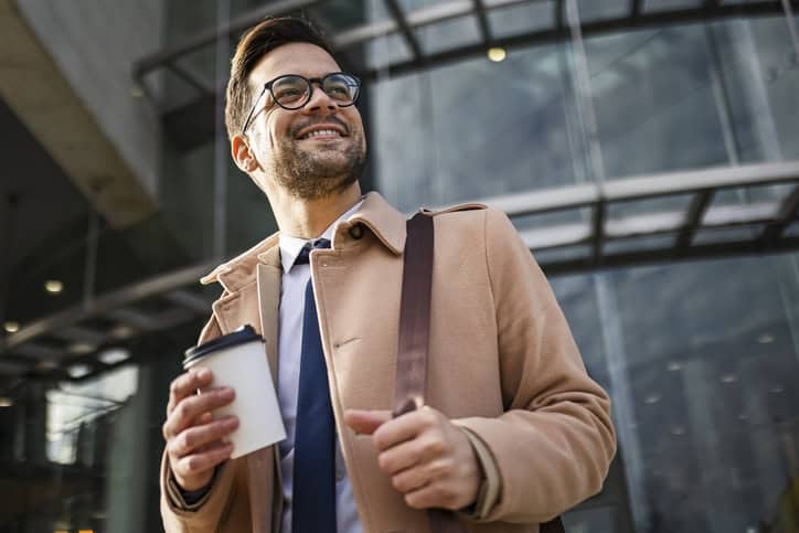 Handsome young businessman walking drinking coffee