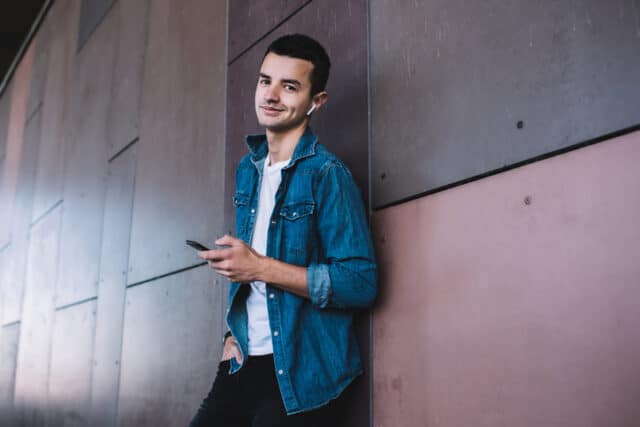trendy guy texting against wall