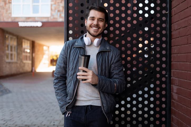 Man in headphones with a coffee on the street.