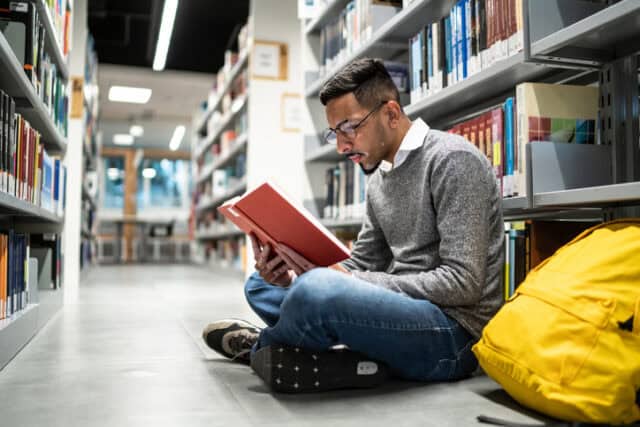 Man sitting on the ground at the library.