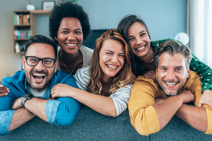 Group of friends sitting on the sofa and smiling.