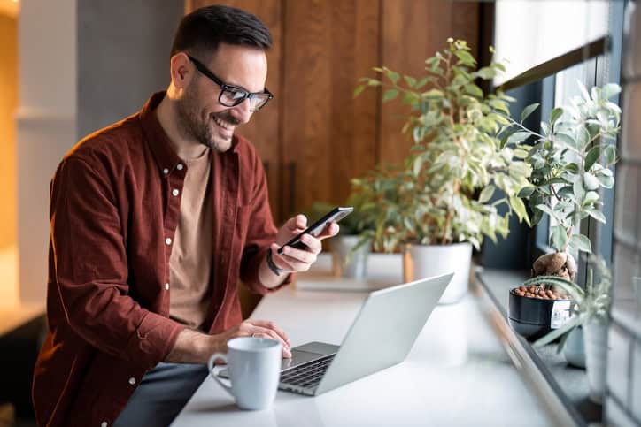 Man on laptop and cell phone.