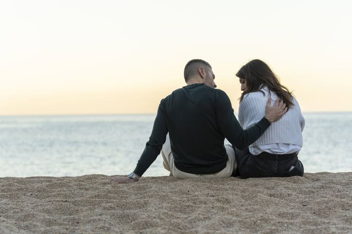 Friends sitting on the beach together. 