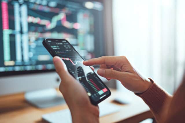 Woman is checking Bitcoin price chart on her smartphone.