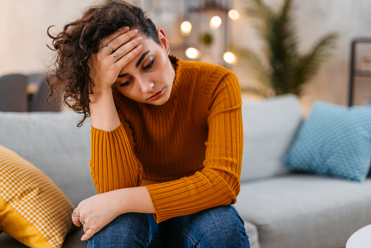 sad woman head in hands on couch