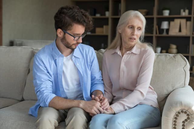 Loving adult son comforting worried concerned senior mother
