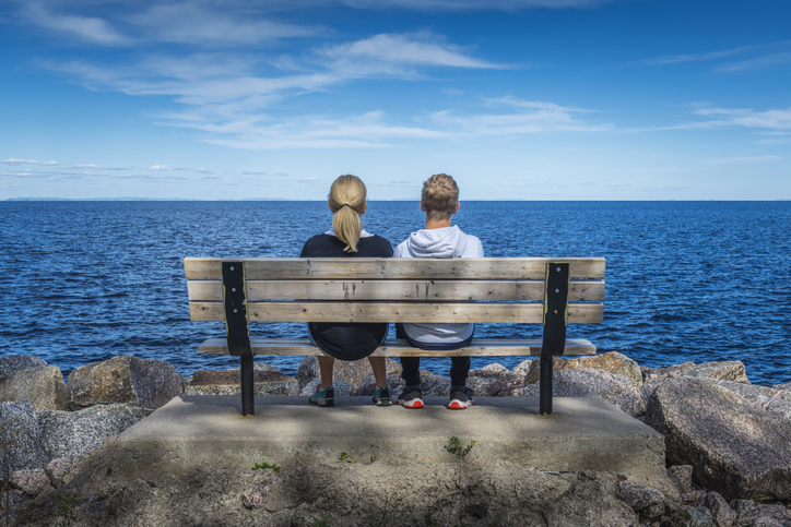 People relaxing on a bench by a lake. 