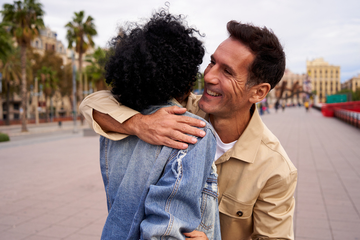Mature caucasian man happily greeting his girlfriend outdoors after a long separation.