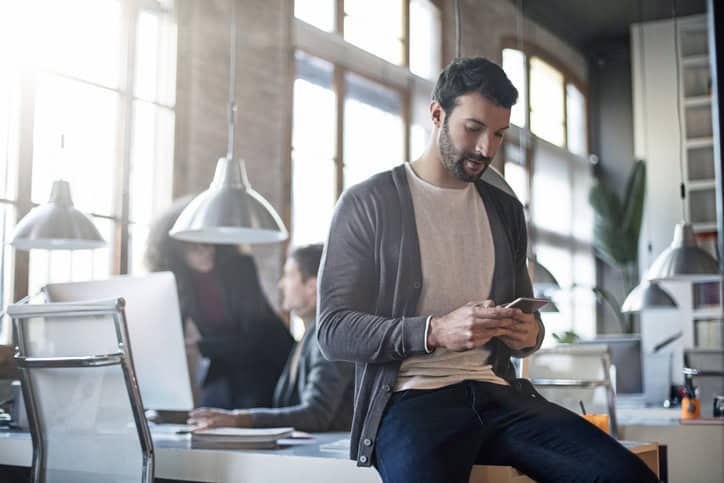 guy texting in office while working