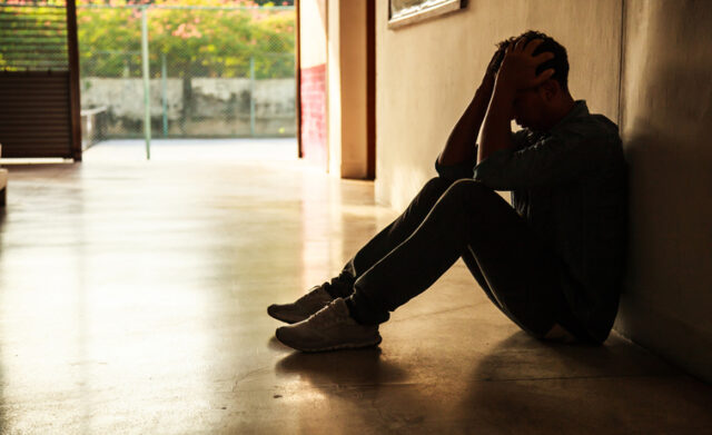 sad man sitting on the floor in shadows