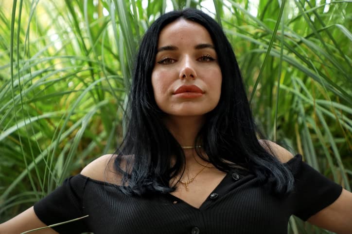 Woman with black hair sitting on a park bench.