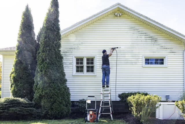 guy power washing house