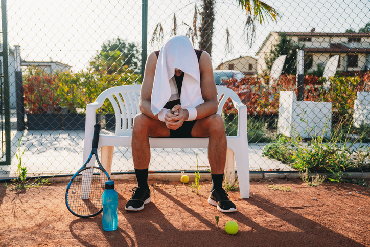 A tennis player resting during a match.